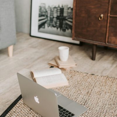 A serene workspace with a laptop, open book, and coffee cup on a textured rug, ideal for remote work.